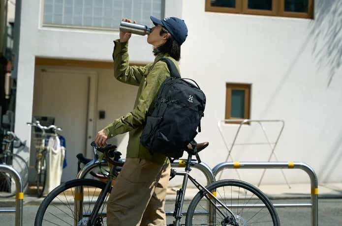 ホグロフスのリュックを背負い自転車を押す男性