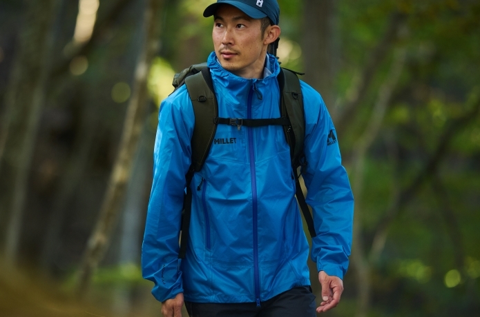 ミレーのレインウェアを着て山を軽快に歩く人