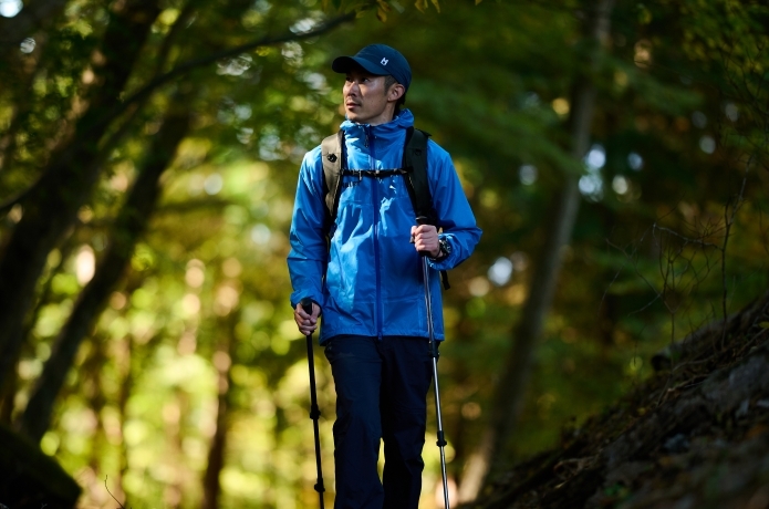 ミレーのレインウェアを着用して森を歩く人