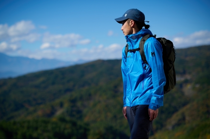 ミレーのレインウェアを着る人と山の景色