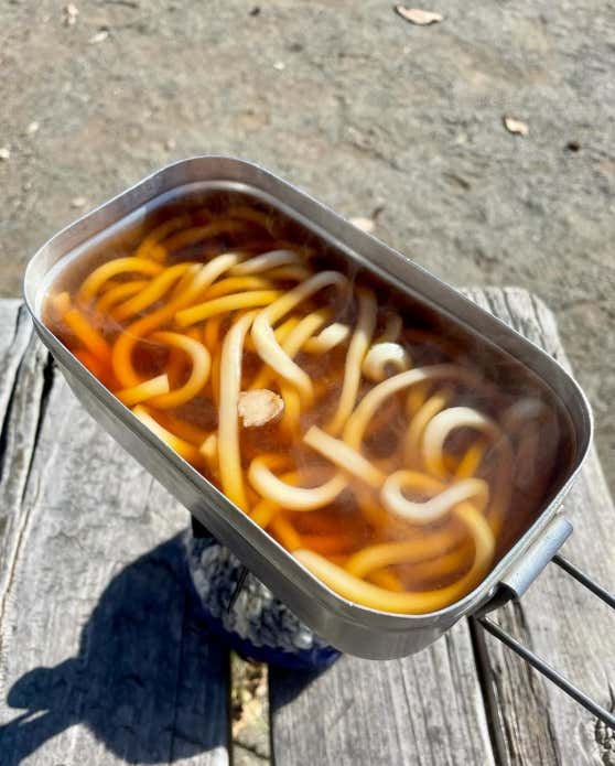 ①七草は食べやすい大きさに切る。②メスティンにうどん、めんつゆを入れて煮込む。