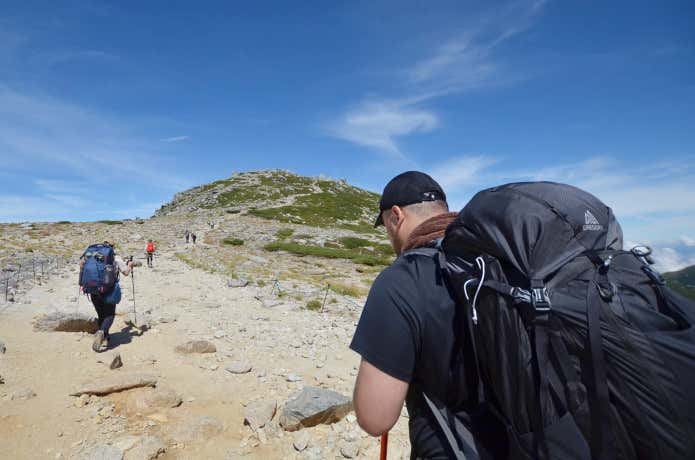大型バックパックを背負って登山する人