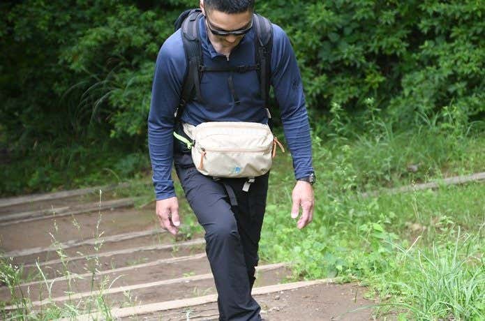 カリマーのウエストバッグをつけて山を登る男性　