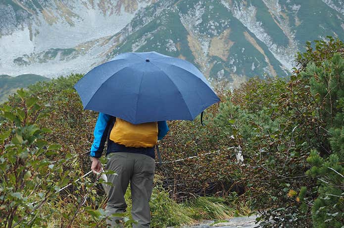 雨で傘をさして登山イメージ