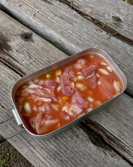 ① 鶏肉は食べやすい大きさに切り、玉ねぎはみじん切りにする。② メスティンに洗ったお米、ケチャップ、コンソメを入れ、内側のリベット(丸い突起)の中心まで水を加える。