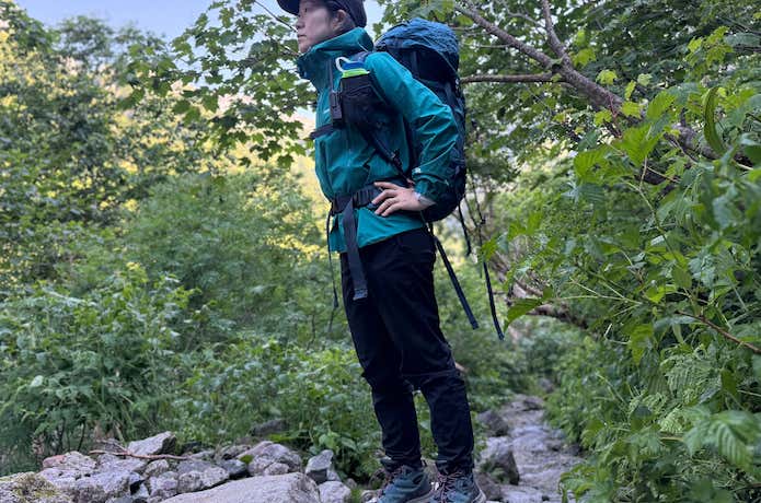 モンベルのストームクルーザー着用の登山者（夏日の樹林帯）