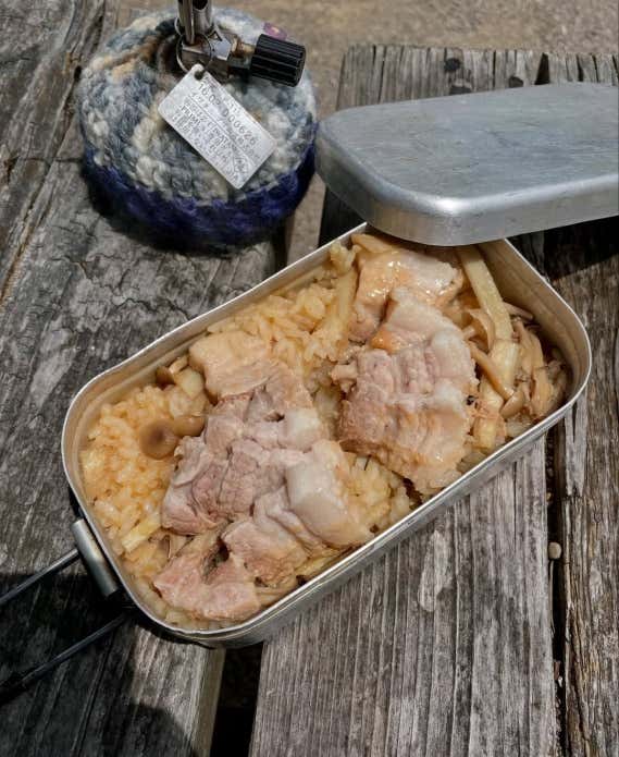 ③ 豚バラ、しめじ、ごぼうをのせて蓋をし、固形燃料で約25分炊飯する。④ 火が消えたら、タオルなどで包んで10分ほど蒸らす。