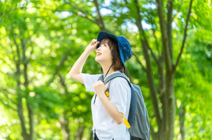 太陽の光を浴びながら森の中を散策する女性