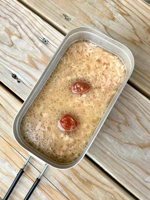 ①メスティンに洗ったお米、チーチキンの汁、醤油、酒、和風だしを入れ、内側のリベット(丸い突起)の中心まで水を加えて調整する
②お米の上にシーチキンの身、梅干しををのせ、フタをして固形燃料で約20分炊く