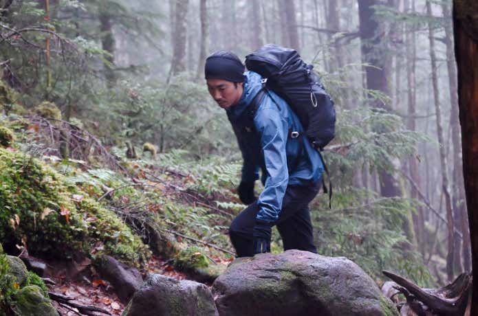 ミューラップフーディを着て樹林帯を歩く人