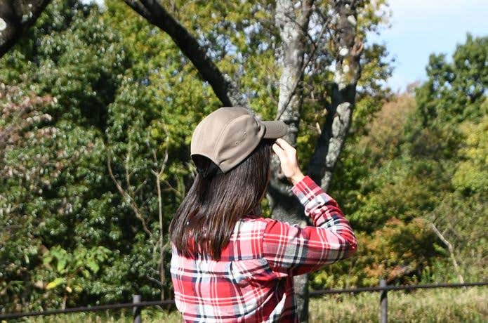 公園を背景にカリマーのウォームキャップをかぶった女性の後ろ姿