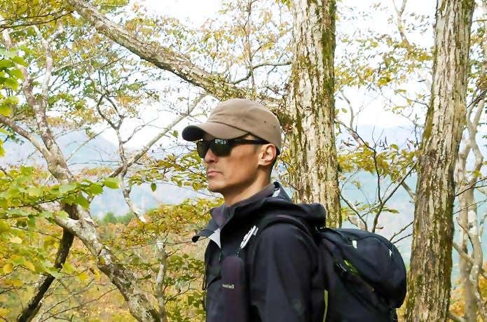 カリマーのウォームキャップをかぶって稜線をバックにたたずむ男性