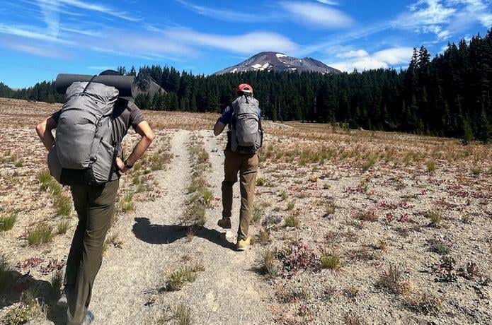 メインバッグとサブバッグが一体になったザックをかついで、山へ向かっている2人