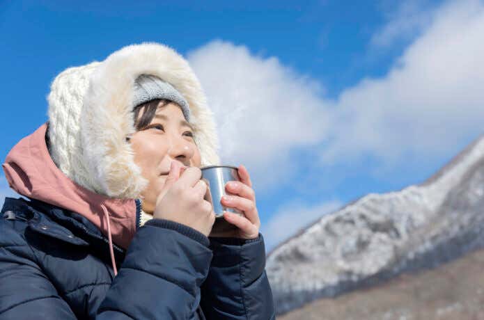 寒い雪山で暖かい飲み物で暖をとる