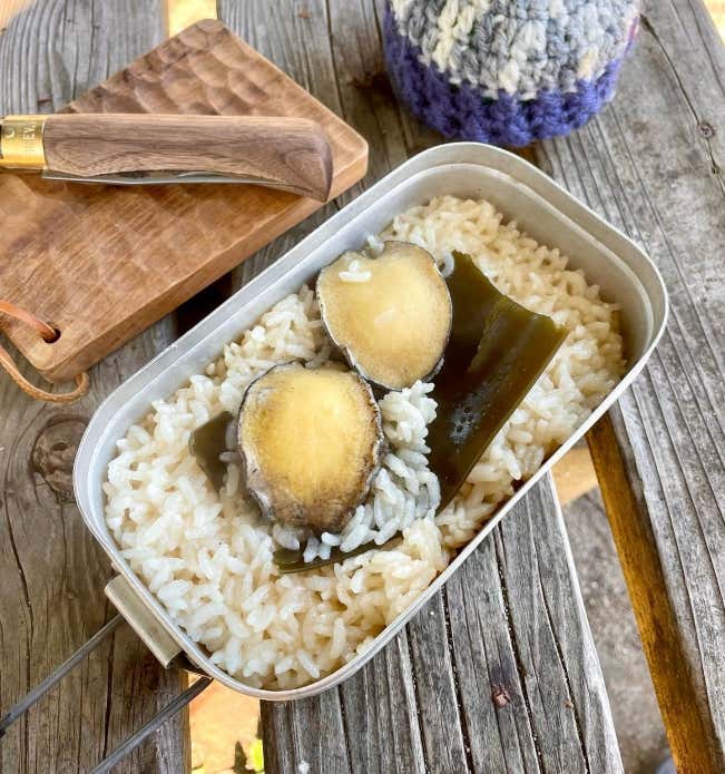 ③ お米の上に昆布の上にあわびをのせ、フタをして固形燃料で約20分炊きます。
④ 火が消えたら、タオルなどで包み10分ほど蒸らします。