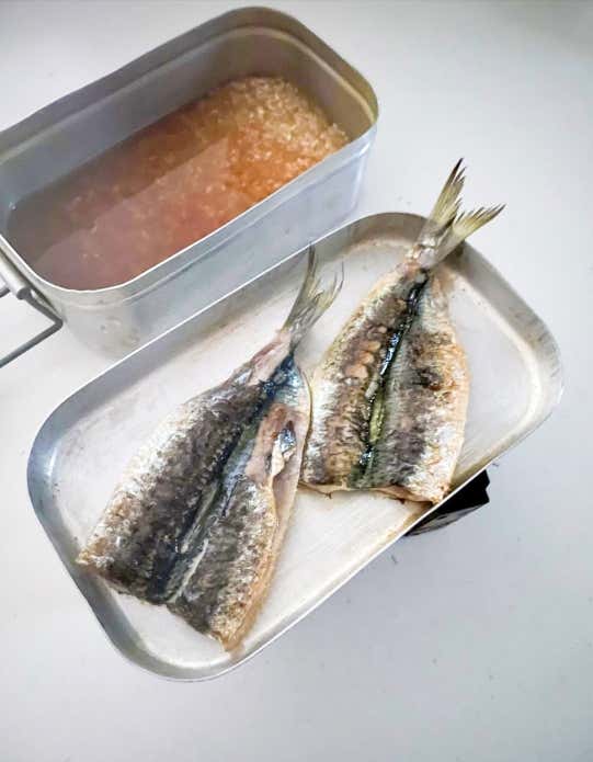 ①メスティンのふたを火にかけ、油は引かず、イワシ（両面）を焼く。