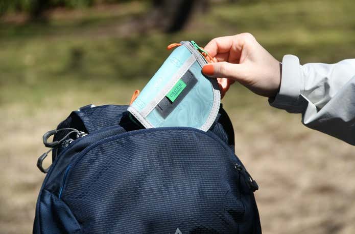 C&C.P.H.EQUIPEMENTのミニ財布をリュックのポケットから取り出しているところ