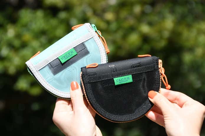 C&C.P.H.EQUIPEMENTのビブラム素材のミニ財布を、色違い2個を重ねて手で持っているところ