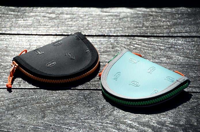 木材の上に置かれたC&C.P.H.EQUIPEMENTのミニ財布の裏面、ビブラムロゴが光るブラック・ターコイズの2色の財布　Vibram®︎