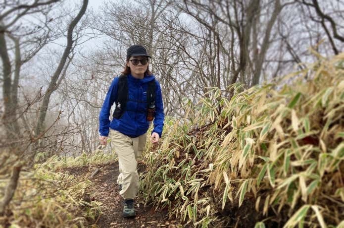 パタゴニアのウィンドブレーカーを着て山を歩く女性