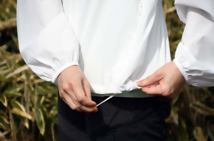 ユニクロ「ポケッタブルUVカットパーカ/NANODESIGN」の裾のドローコードを絞っているところ