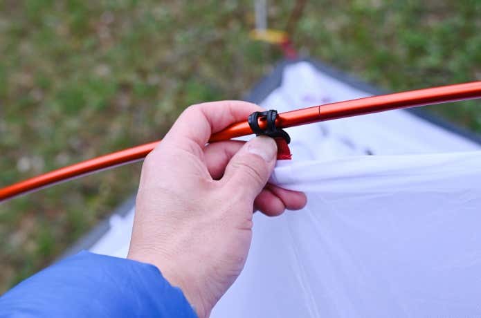 テント本体のフックをポールに引っ掛ける様子