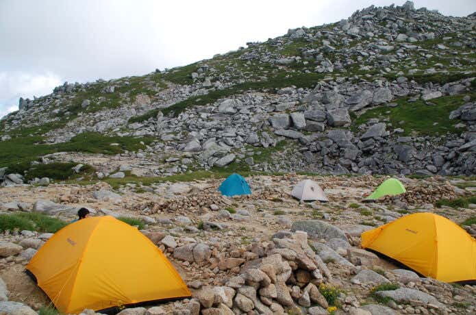 モンベルのテントを稜線で張る登山者