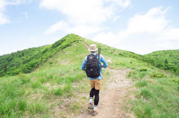 ショートパンツを履いて山を歩く人の後ろ姿
