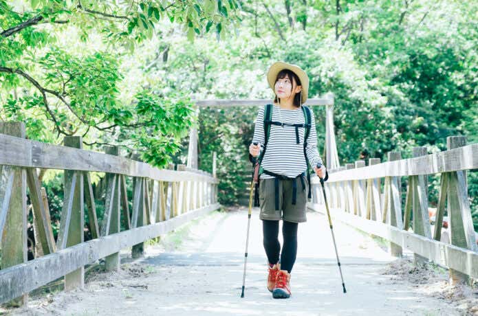 ショートパンツを履いて山の中の橋をわたる女性