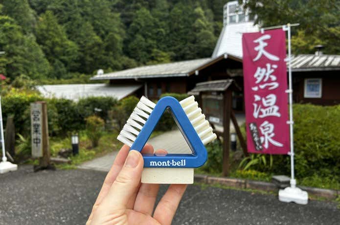 日帰り温泉の入口でモンベル 3-Wayブーツメンテナンスブラシを手に持つ様子