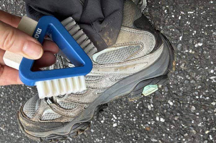 モンベル 3-Wayブーツメンテナンスブラシで登山靴とパンツの裾の土汚れを落とす様子